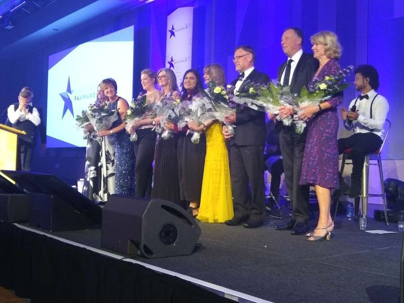 Administrative professionals receiving flowers and applause on an awards stage