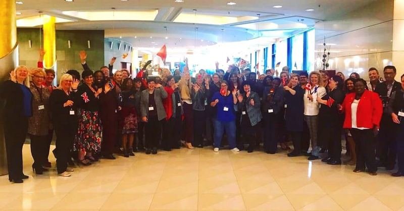 An international gathering of IAM members and administrative professionals waving flags of many nations
