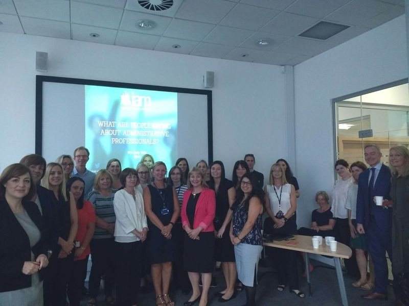 A large workplace team gathered for an IAM session on administrative professionals